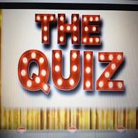 Signage for "The Quiz" illuminated marquee sign in a vibrant indoor setting.
