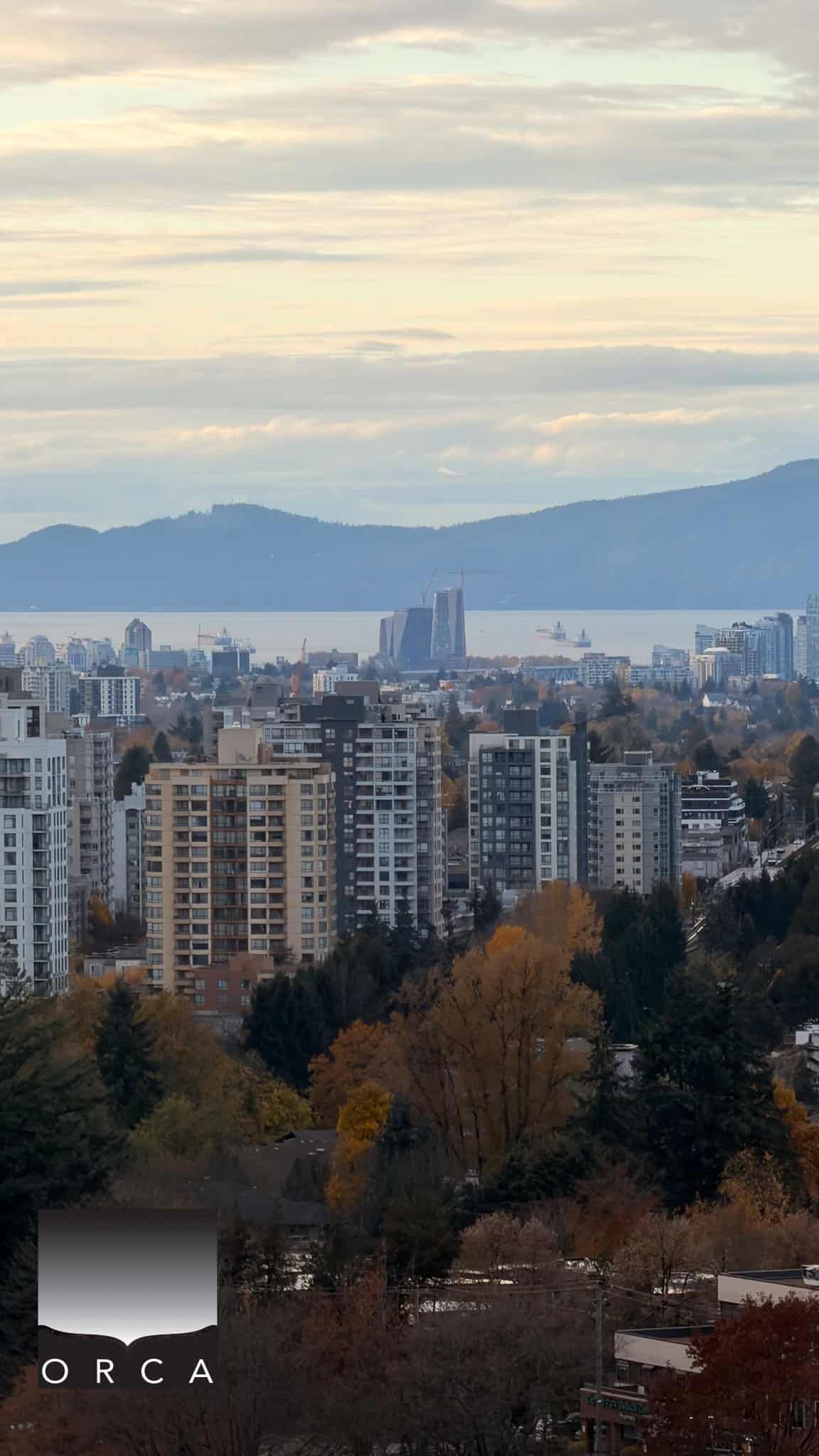 Vancouver city skyline with water view, residential buildings, and mountain backdrop in autumn, showcasing real estate opportunities in Vancouver, BC.