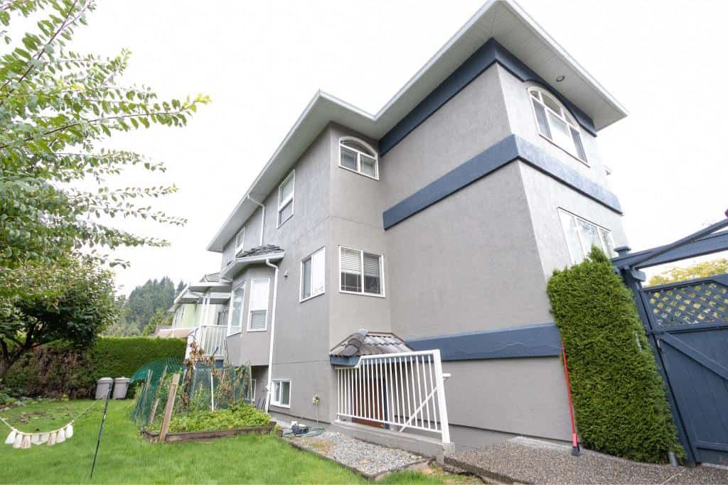 Modern multi-story residential home in Vancouver with well-maintained lawn, garden, and privacy fencing, showcasing professional real estate services by Orca Realty Inc.