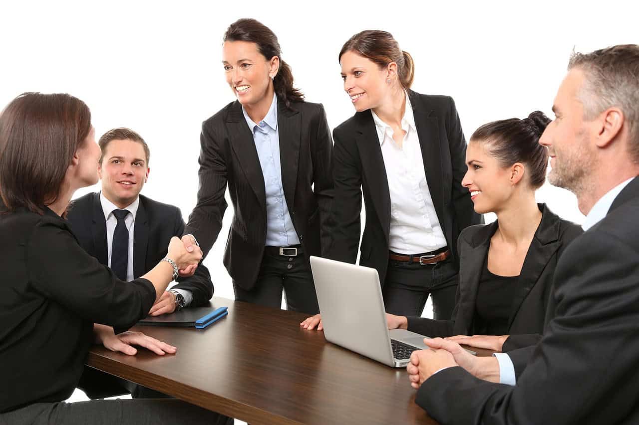 Experienced real estate agents at Orca Realty Inc. shaking hands and discussing property opportunities in a professional office setting.