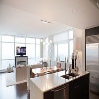 Modern open-concept living and dining area in a high-rise apartment with large windows offering panoramic city views. Stylish furniture, bright natural light, and contemporary decor.