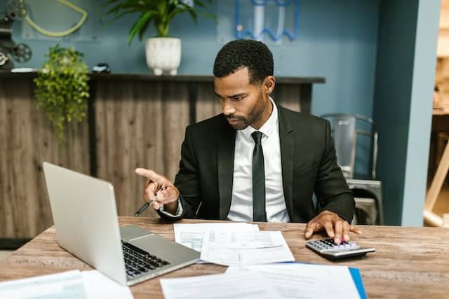man at computer with papers and caluclator