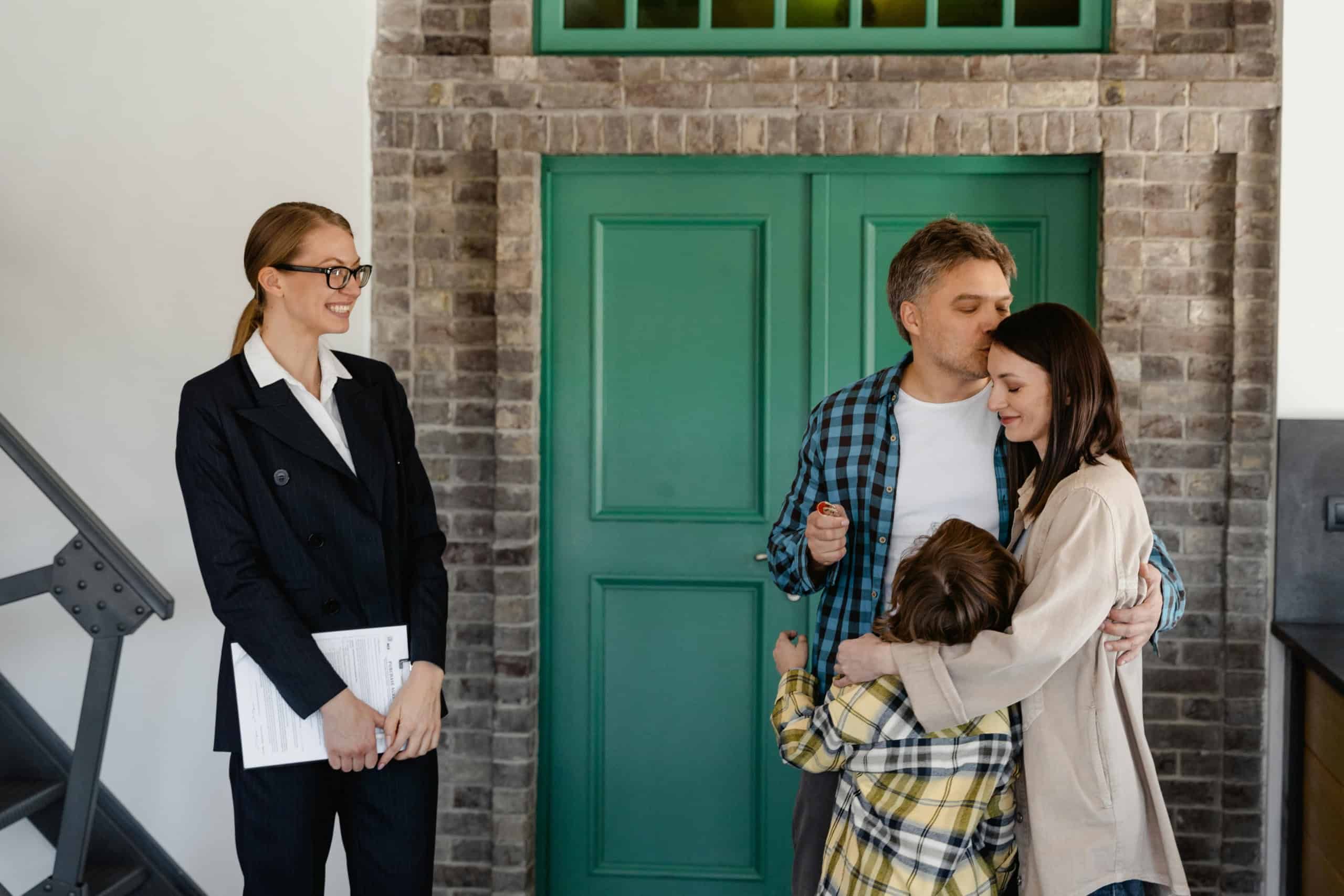 Modern family moving into a new home, experiencing a joyful moment with a real estate agent celebrating their home purchase, inside a stylish brick and green door entryway.