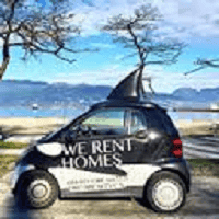 Orca realty inc. car with "WE RENT HOMES" signage parked near a lakeside with trees and mountains in the background, showcasing property rental services in Ontario.