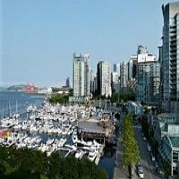 Marina and city skyline in Vancouver, British Columbia, featuring luxury yachts, modern high-rise buildings, and scenic waterfront views.
