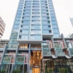 Modern high-rise condominium building with glass exterior, Vancouver city skyline, urban residential living, contemporary architecture, and luxurious amenities.
