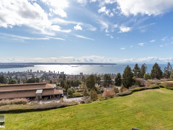 Breathtaking panoramic view of Vancouver’s skyline and waterfront from a lush residential property on elevated terrain, showcasing real estate opportunities with Orca Realty Inc.