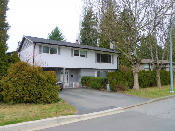 Modern two-story house with a grey and white exterior, surrounded by lush greenery, situated in a peaceful neighbourhood in Nanaimo, BC.