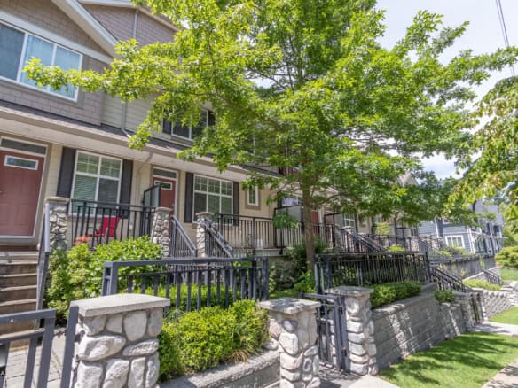Modern townhouse row with inviting porch, landscaped gardens, and vibrant greenery in a desirable neighbourhood. Perfect for families looking for comfort and community.