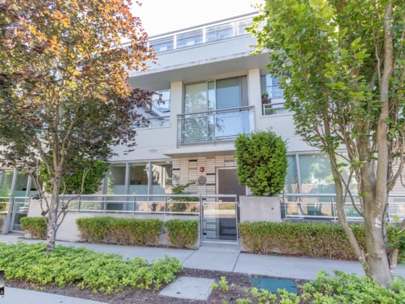 Bright modern condo building with landscaped front yard, trees, and balcony, showcasing urban living and prime real estate in Vancouver.