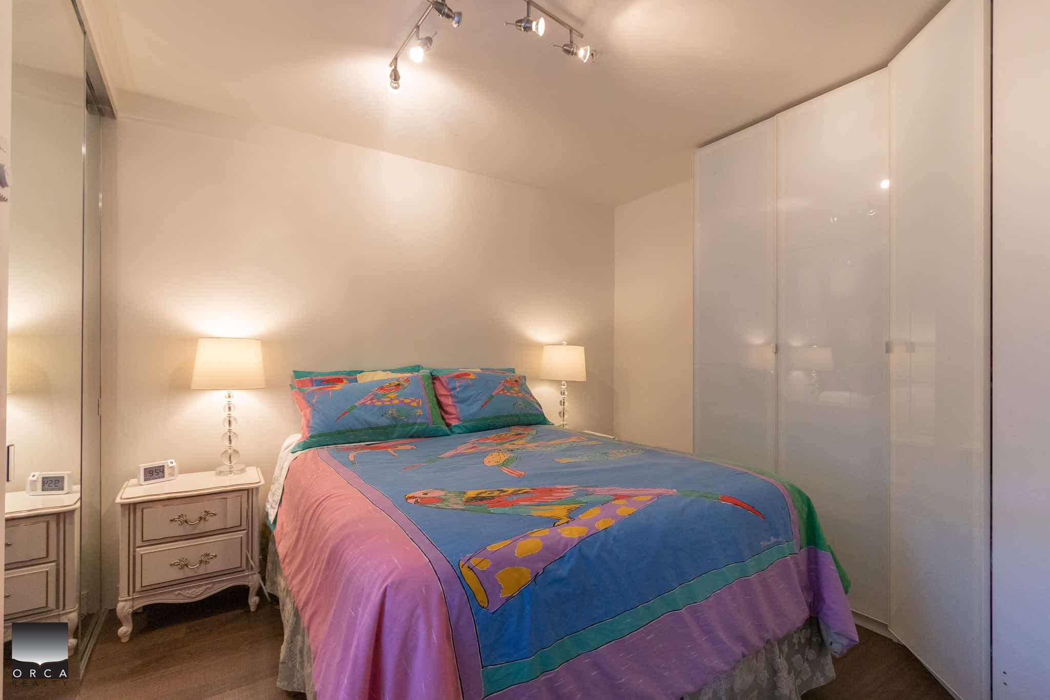 Comfortable bedroom with colorful bedding, modern lighting, and ample closet space, perfect for Vancouver Island real estate buyers.