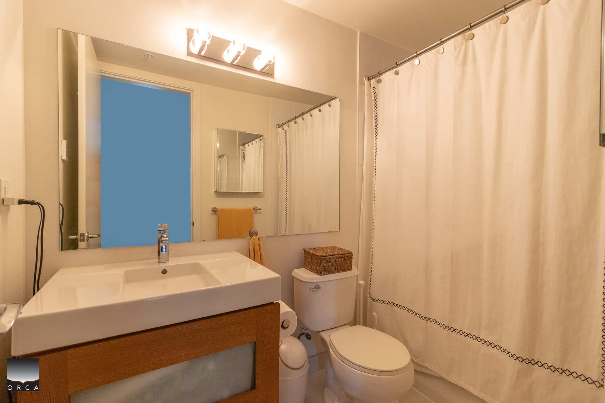 Modern bathroom featuring a white sink, mirror, and shower curtain, ideal for Vancouver and British Columbia homes, showcasing Orca Realty Inc.'s expertise in BC real estate.