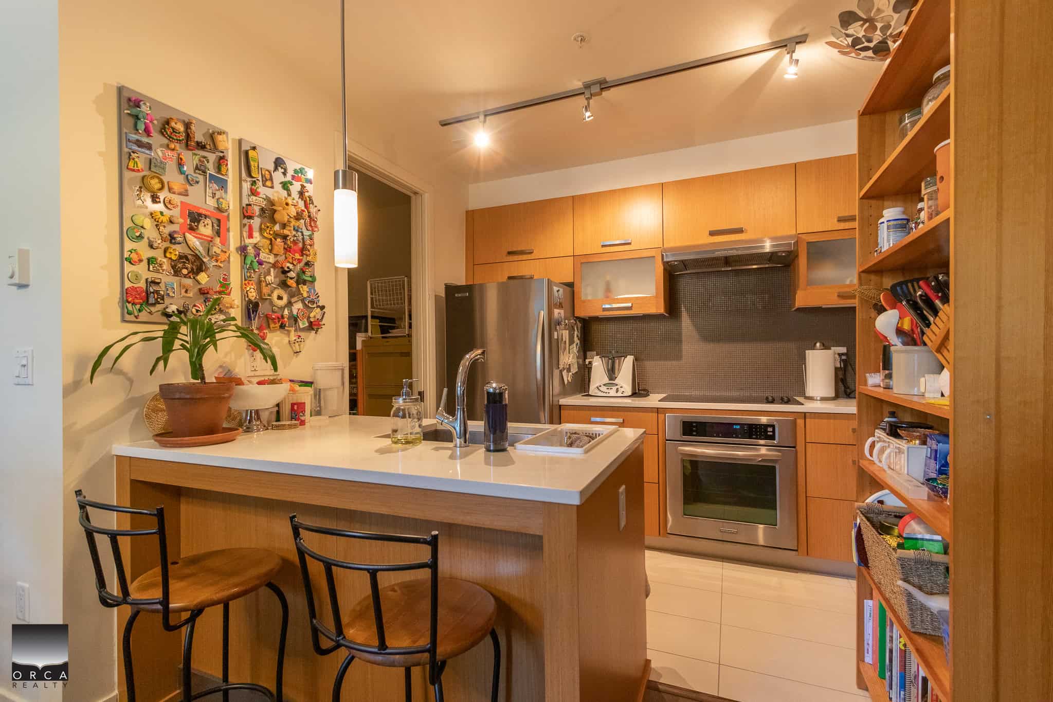 Bright modern kitchen with warm wooden cabinetry, stainless steel appliances, and a cozy breakfast bar ideal for family gatherings and cooking enthusiasts.