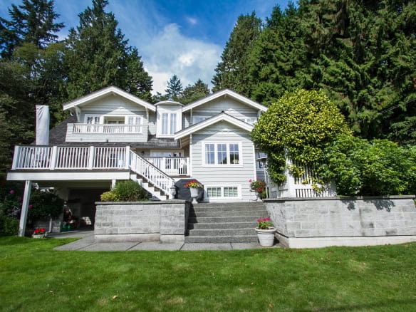 Beautiful multi-story house with white exterior, surrounded by lush greenery and mature trees, showcasing expert real estate services by Orca Realty Inc.
