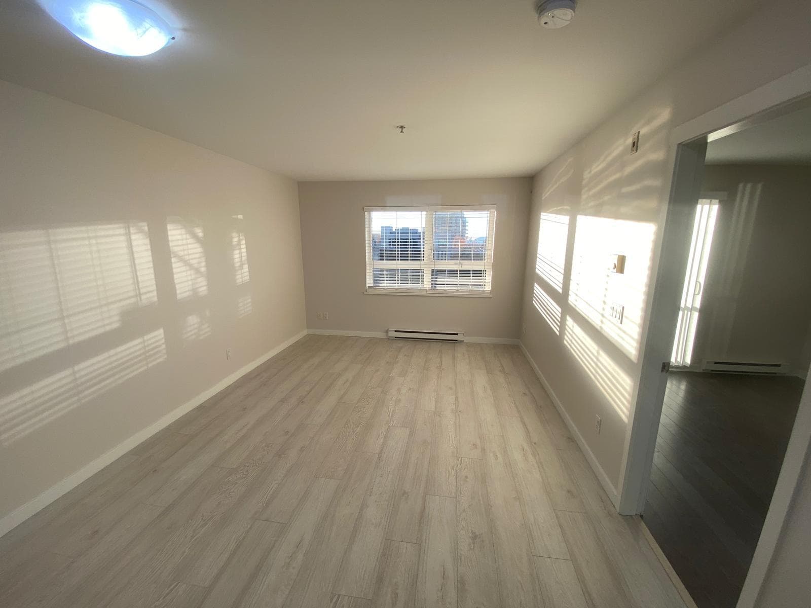 Bright and spacious living room in a modern condo with large windows and natural light, featuring light hardwood flooring and neutral walls, perfect for stylish interiors.