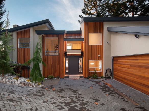 Contemporary residential home with modern design, featuring wooden accents and large windows, located in a scenic natural setting on Vancouver Island, BC.