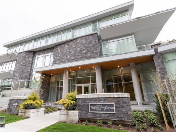 Contemporary multi-storey apartment building with modern glass and stone facade, located in Vancouver, BC, showcasing upscale residential real estate by Orca Realty Inc.