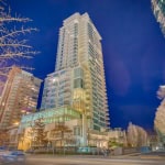 Modern high-rise condominium building in downtown Vancouver at night, showcasing luxury residential apartments with cityscape views. Perfect for Vancouver real estate investment or new homebuyers.