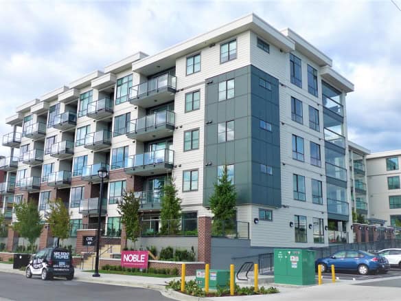 Modern multi-family residential building with contemporary design, glass balconies, and urban landscape—ideal property for Vancouver real estate investment and living.