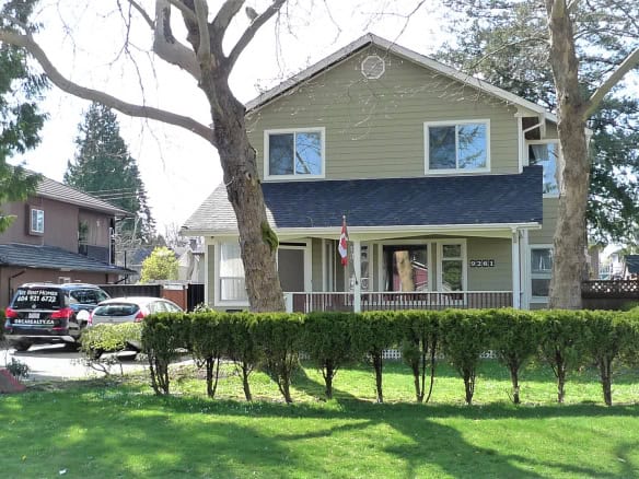 Charming two-storey house listed by Orca Realty Inc. in a friendly Vancouver neighbourhood, featuring a spacious front yard, mature trees, and a welcoming porch, perfect for families and investors.