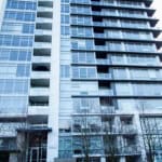 Modern high-rise condominium building with glass exterior and spacious balconies in Vancouver, BC.
