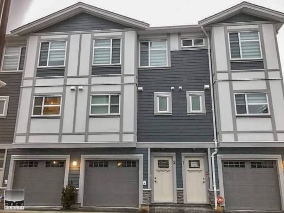 Modern multi-family townhouse with contemporary design, featuring grey and white exterior, double garages, and multiple windows in Vancouver area. Perfect for real estate buyers.