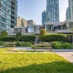 Modern urban residential complex with lush landscaped garden and outdoor seating area, overlooking high-rise condos in Vancouver, BC, ideal for luxury living and real estate investment.