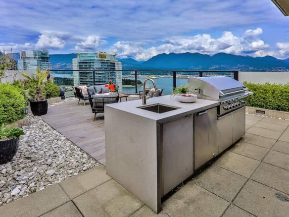 Modern rooftop outdoor kitchen with BBQ grill, patio seating, and cityscape view, perfect for Vancouver waterfront real estate and luxury condo living in British Columbia.