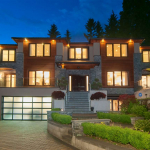 Luxurious modern home exterior at dusk with illuminated windows, landscaped garden, and contemporary architecture, showcasing upscale real estate in Vancouver, BC for Orca Realty Inc.