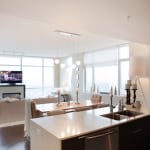 Modern open-concept living room and kitchen in downtown Vancouver with large windows, contemporary furniture, and urban city views.