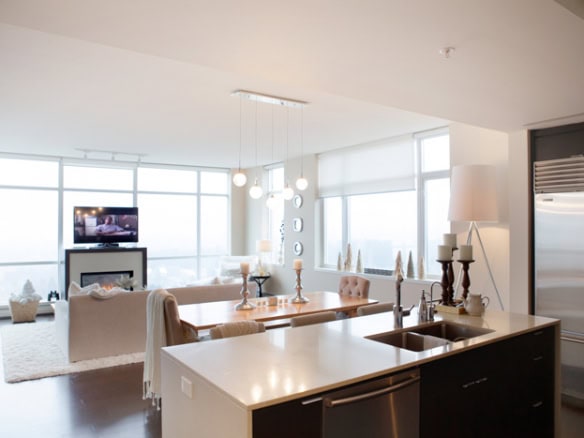 Modern open-concept living room and kitchen in downtown Vancouver with large windows, contemporary furniture, and urban city views.
