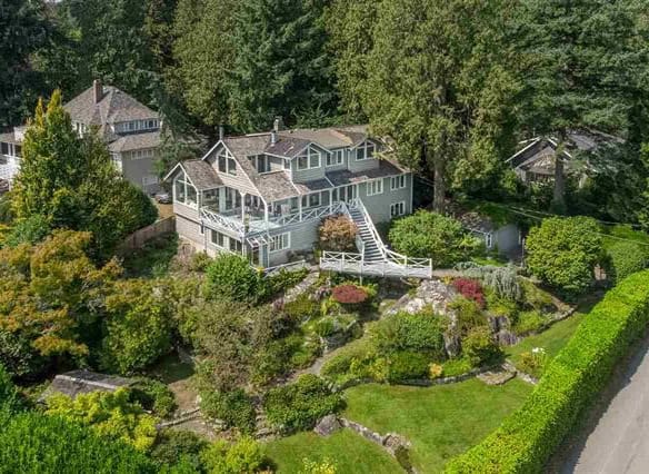 Aerial view of a large, modern house surrounded by lush greenery and colorful landscaping in a suburban neighbourhood in Vancouver, BC.