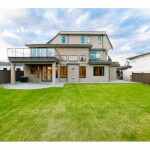 Spacious modern backyard with lush green lawn and contemporary house design in Vancouver, BC. Perfect for family gatherings and outdoor entertaining.