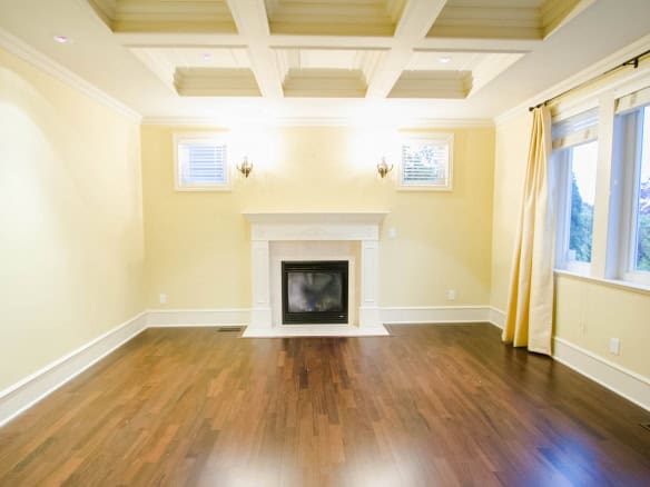 Spacious living room with a cozy fireplace, large windows, and elegant yellow walls, perfect for family gatherings and entertaining guests in a charming Canadian home.