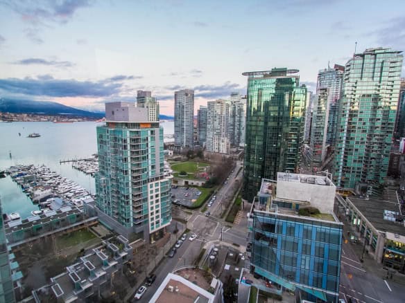 Vibrant Vancouver skyline with modern high-rise condos and marina view, showcasing the prime real estate appealing for buyers seeking waterfront properties in BC.