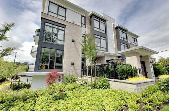 Modern multi-story residential building with large windows and landscaped garden in Vancouver, BC. Prime real estate property for sale or rent by Orca Realty Inc.