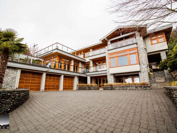 Stunning modern house exterior featuring large windows, stone accents, and a spacious driveway, perfect for luxury real estate in BC by Orca Realty Inc.
