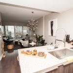 Contemporary open-concept apartment with modern kitchen and living area, city views, stylish decor, and high-end finishes, ideal for Vancouver real estate buyers.