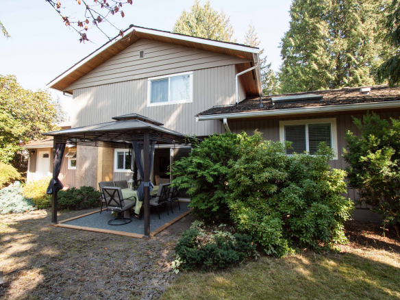 Spacious backyard with outdoor patio and furniture, surrounded by lush greenery, perfect for relaxing and entertaining, in a family-friendly residential home.