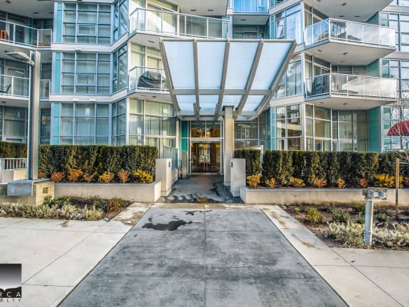 Modern condominium building entrance with glass balconies and landscaped pathway, offering luxury Vancouver real estate options and upscale apartment living in British Columbia.