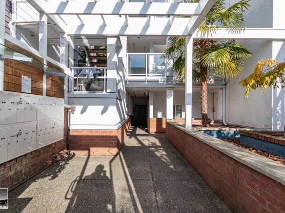 Mailboxes near condo entrance with palm trees in the courtyard - Orca Realty Inc.