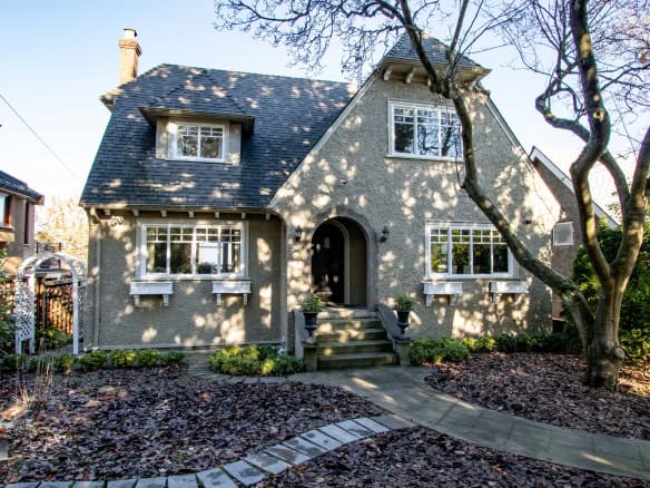 Charming Vancouver-style home with a textured exterior, surrounded by mature trees and lush landscaping, available through Orca Realty Inc., showcasing prime real estate in British Columbia.
