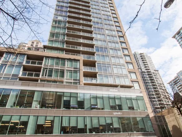 Modern high-rise condominium building downtown Vancouver with glass exterior, residential units, and commercial spaces, highlighting Vancouver real estate opportunities and luxury apartment living in Canada.