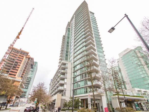 Modern downtown Vancouver high-rise condominium with glass facade and spacious balconies, ideal for urban living and investment.