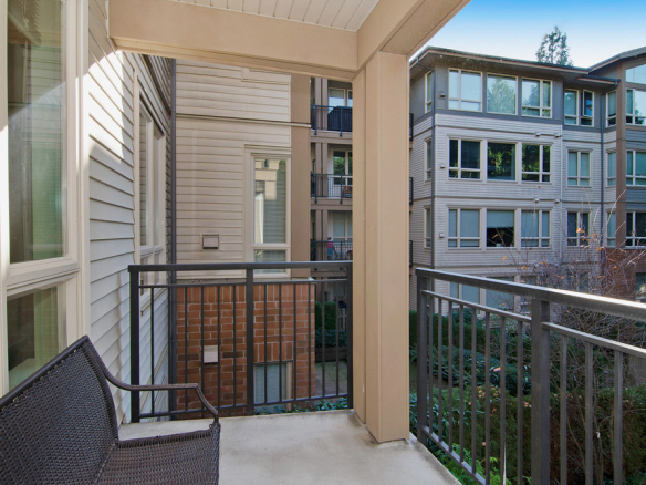 Modern apartment balcony overlooking neighbouring residential buildings with large windows, surrounded by greenery, ideal for outdoor relaxation in Vancouver.