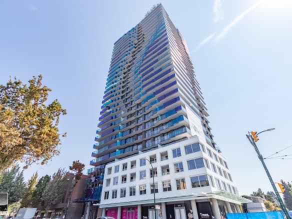 Modern downtown Vancouver high-rise condominium building with glass balconies, city views, and commercial retail spaces at the ground level.