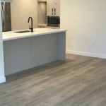 Bright, modern kitchen with white cabinetry, a sleek island, black fixtures, stainless steel appliances, and light wood flooring, perfect for contemporary Vancouver Island homes for sale.