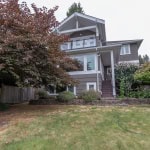 Spacious multi-level home with modern design and lush landscaping in a peaceful neighbourhood, featuring large windows, a backyard garden, and a well-maintained lawn.