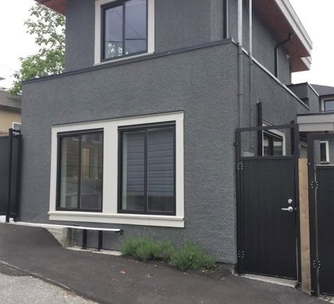 Modern two-storey grey residential building with large windows and black accent details, located in Vancouver, BC, ideal for Vancouver real estate investment.