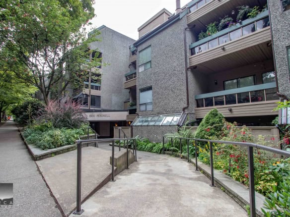Lush landscaped pathway leading to the entrance of Orca Realty Inc. building, surrounded by vibrant greenery and flowers, in a peaceful Vancouver neighbourhood.